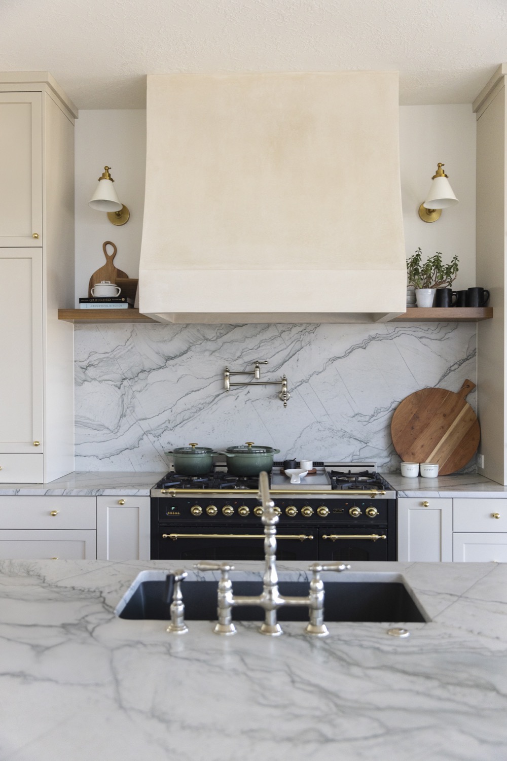 Warm cream kitchen with natural wood shelves and brass fixtures